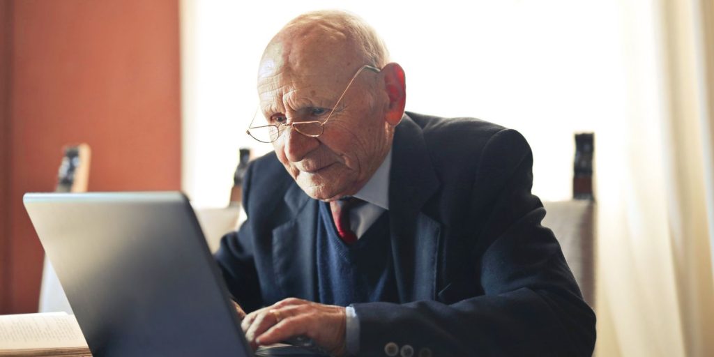 Serious Senior Man In Formal Suit Working On Laptop At Workplace.jpg