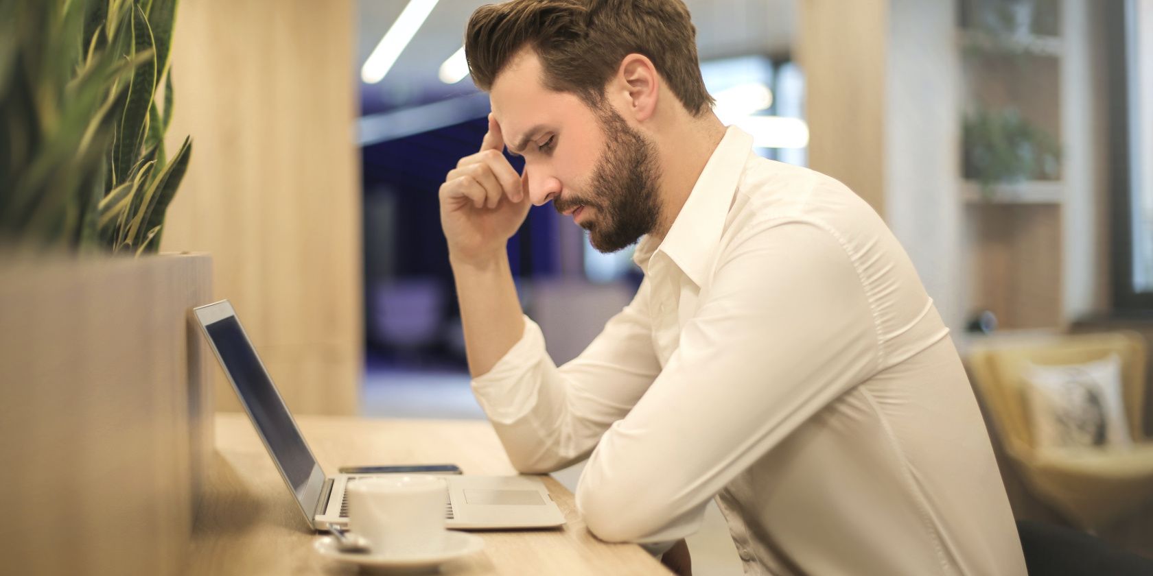 Hand On Forehead Of A Man Looking At A Laptop.jpg