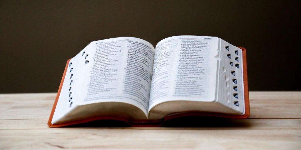 Large dictionary open halfway and propped up on wooden table.jpg