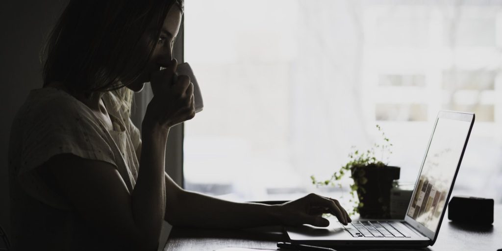 A girl sips a beverage while working on her laptop.jpg