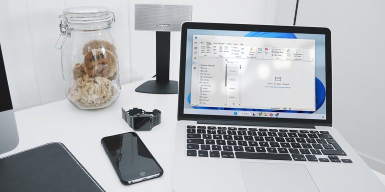 A Silver Laptop Running Outlook On A White Table.jpg