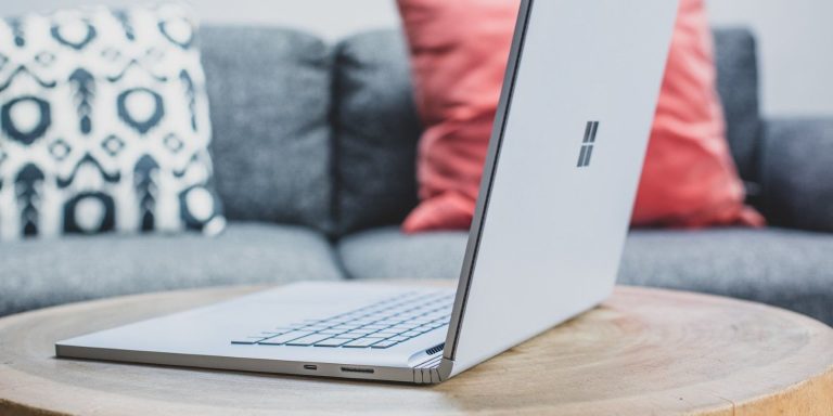 A Silver Windows Laptop On A Round Wooden Table.jpg