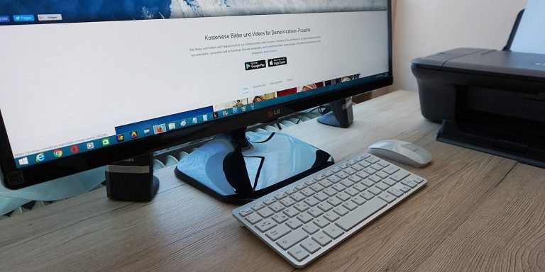 A Monitor On A Wooden Table Next To A Printer.jpg